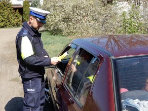 policjant ruchu drogowego podczas sprawdzania stanu trzeźwości urządzeniem