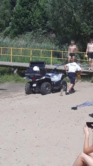 Zdjęcie przedstawia policjanta biegnącego pomóc osobie tonącej podczas pokazów dla dzieci