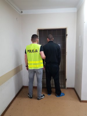 Zdjęcie pokazuje zatrzymaną osobę do włamania podczas czynności z funkcjonariuszem Policji