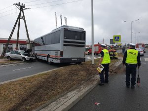 Zdjęcie pokazuje policjantów podczas czynności w sprawie wypadku z udziałem autobusu i pojazdu osobowego