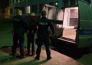 policjanci wyprowadzają zatrzymanego z radiowozu