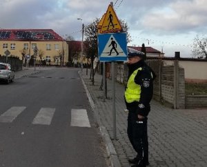 Zdjęcie przedstawia policjanta ruchu drogowego pełniącego służbę w okolicy przejścia dla pieszych