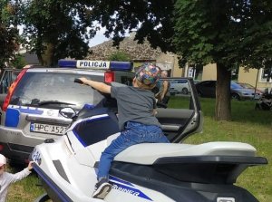 Policjanci podczas pikniku prezentują sprzęt dzieciom