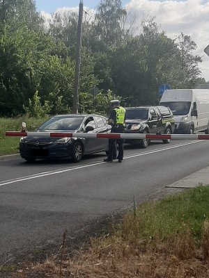 policjant rozmawiający z kierowcą przy szlabanie kolejowym