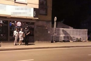 policjant i pracownicy Sanepidu przed kontrolowanym lokalem