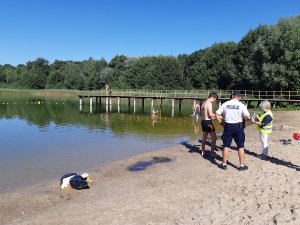 policjant i pracownik Sanepidu rozdają ulotki plażowiczom