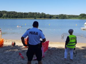 policjant i pracownik Sanepidu sprawdzają czy plażowicze przestrzegają obostrzeń