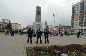 policjanci sprawdzają czy osoby zgromadzone na Placu Wolności stosują się do obostrzeń