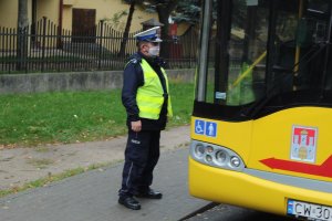 Policjant ruchu drogowego stojący przy wejściu do autobusu komunikacji publicznej