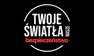 Na środku napis twoje światła nasze bezpieczeństwo otoczone białym kołem. Tło jest czarne