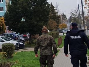 Po prawej policjant, a po środku żołnierz wot podczas kontroli kwarantanny, z tyłu widoczny blok