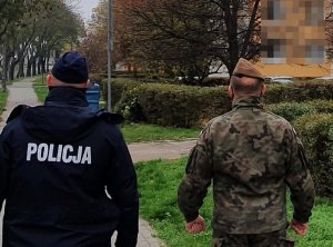 Po lewej policjant, a po prawej żołnierz wot podczas kontroli kwarantanny, z tyłu widoczny blok