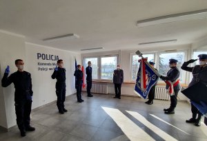 Od lewej strony nowi policjanci podczas ślubowania a po prawej sztandar policji