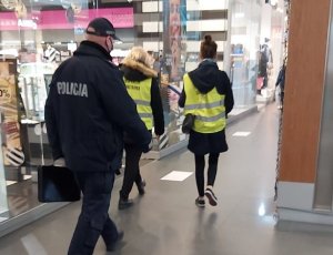 Policjant wspólnie z inspekcją sanitarna kontroluje placówki handlowe. Zdjęcie do treści informacji