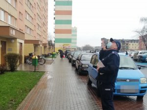 Policjant podczas sprawdzania kwarantanny stoi przed blokiem