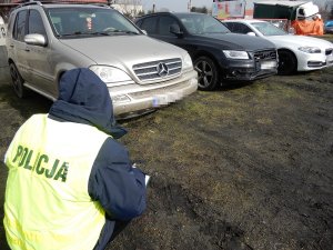 Policjant podczas czynności przy zabezpieczonych pojazdach