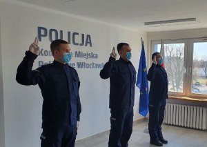 Trzech policjantów podczas przyjęcia ślubowania w pomieszczeniu. Z tyłu napis Komenda Miejska Policji we Włocławku