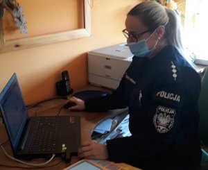 Policjantka w umundurowaniu podczas spotkania z uczniami za pomocą komputera zgodnie z treścią komunikatu