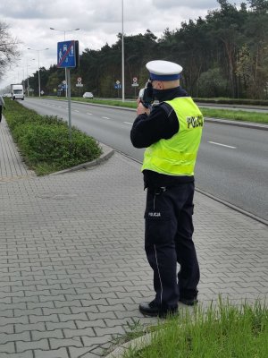 Policjant podczas działań na drogach mierzy prędkość urządzeniem