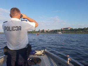 Policjant podczas obserwacji rzeki z łodzi patrolowej