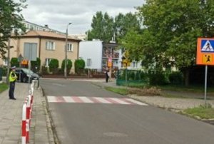 Policjant podczas sprawdzania oznakowania przed szkołą