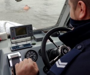 Widok z kabiny policyjnej łodzi na rzekę.