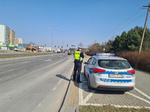 Policjant stojący przy radiowozie podczas działań na drodze