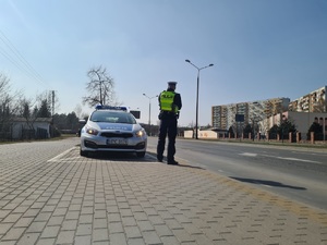 Zdjęcie poglądowe. stojący radiowóz i w pobliżu niego policjant