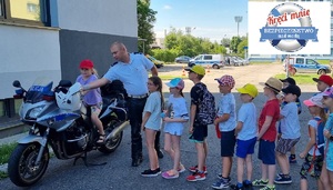 Dzieci podczas wizyty w komendzie. Dzieci stoją przy policyjnym motocyklu