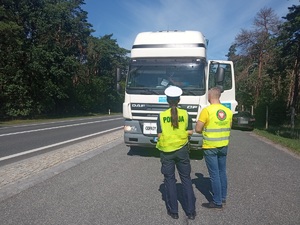 Policjant wspólnie z inspektorami Wojewódzkiego Inspektoratu Ochrony Środowiska podczas kontroli pojazdów