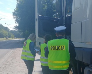Policjant wspólnie z inspektorami Wojewódzkiego Inspektoratu Ochrony Środowiska podczas kontroli pojazdów