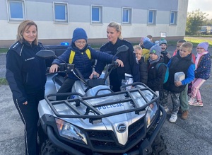 Na zewnątrz stoją policjanci wraz z grupą dzieci