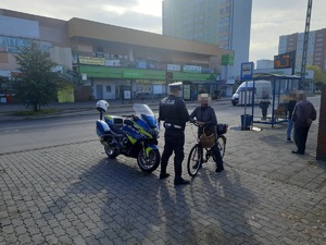 Policjant ruchu drogowego stojący przy policyjnym motocyklu podczas kontroli