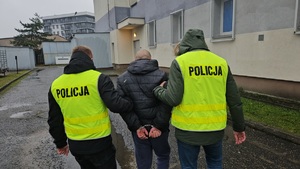 Policjanci podczas doprowadzania osoby do pomieszczenia dla osób zatrzymanych