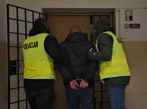 Policjanci podczas doprowadzania osoby do pomieszczenia dla osób zatrzymanych