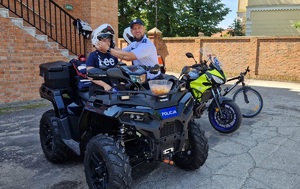 Policjanci podczas pikniku prezentują motocykl policyjny i quada