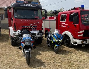 Policyjne motocykle na pierwszym planie, w tle widoczne wozy bojowe straży pożarnej