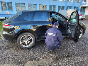 Policjant podczas czynności przy zabezpieczonym pojeździe